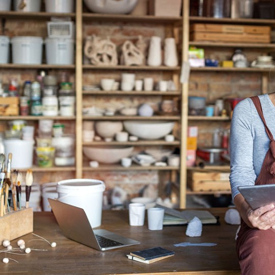 Senior woman with an iPad sitting on table in front of a bunch of shelves