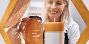 Woman displaying honey jars on shop front