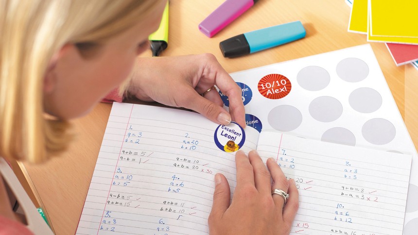 A teacher applying Avery printable merit stickers