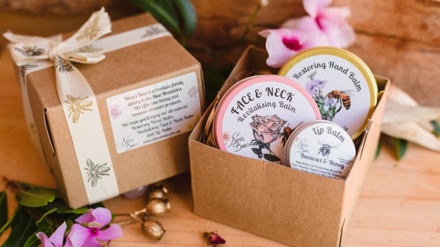 2 brown boxes, one gift wrapped with patterned ribbon and one containing a mixture of round containers with printed lids.