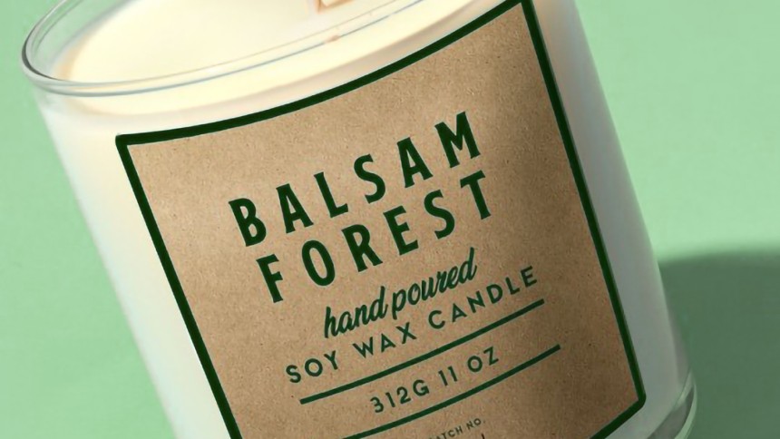 Green background with candle jar. On jar is a kraft brown label with the text Balsam Forest.