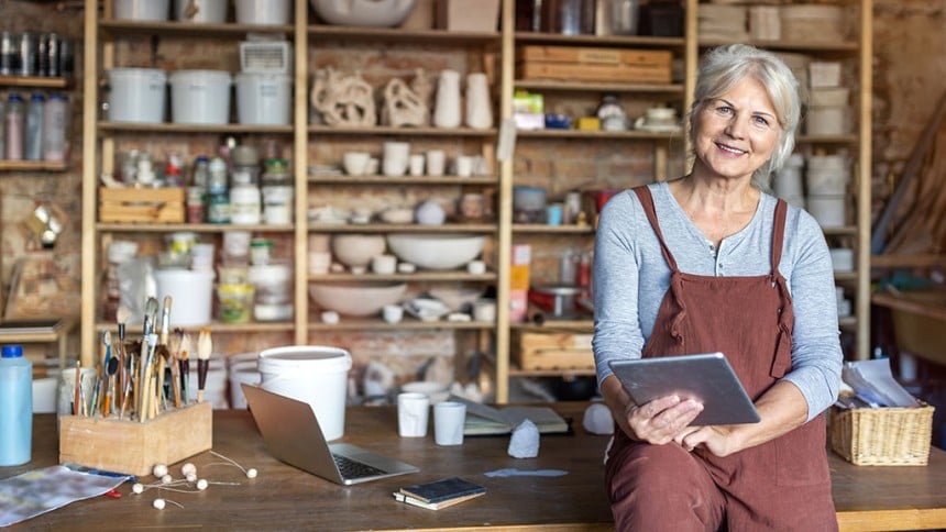 Senior woman with an iPad sitting on table in front of a bunch of shelves