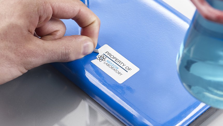 Person's hands trying to peel off labels off a blue surface that are not coming off properly.