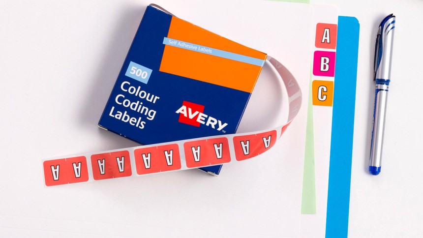 Colour Coding Alphabet Labels in a roll strip placed on top of a folder organised with alphabets on office desk.