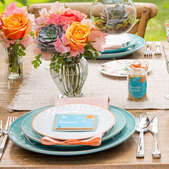 Garden party with table decorated in flowers and plants with custom made place cards and jars with round labels.