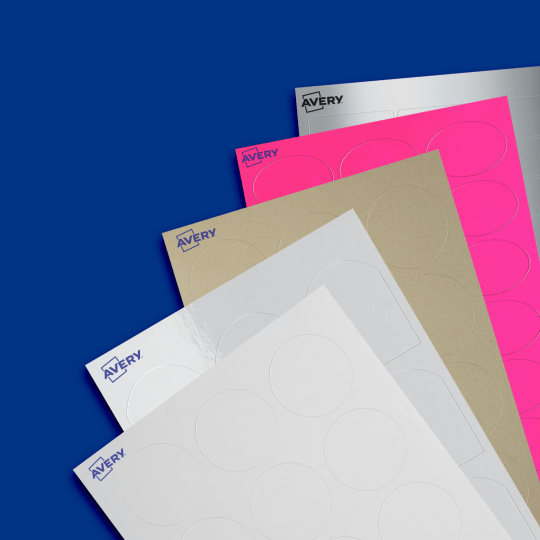 This image features many blank samples of labels spread diagonally. They all; have different colours and shapes. Colours include white, gloss, Kraft brown, hot pink and metallic silver