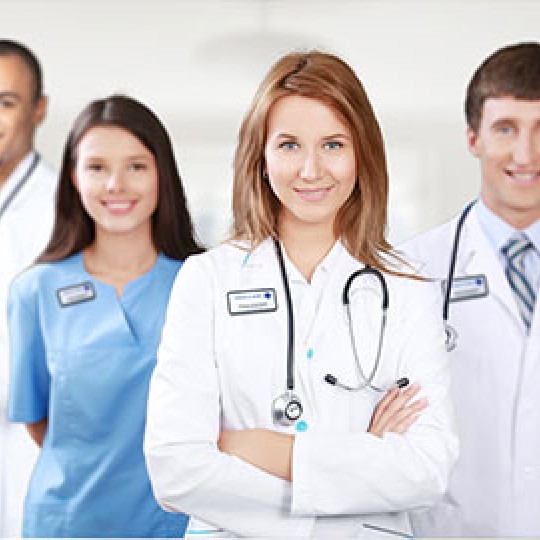 4 medical professionals, 2 male and 2 female, facing the camera, smiling. All are wearing name badges.