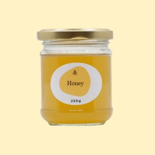 A front view of a short, wide, transparent glass jar of honey with a gold lid. The label is a white oval with a repeating honeycomb pattern. In the center of the label, there is an abstract, golden-yellow shape with a small illustration of a bee and the text "Honey". Below this, the text "250g" is printed. The jar is set against a plain, light yellow background.