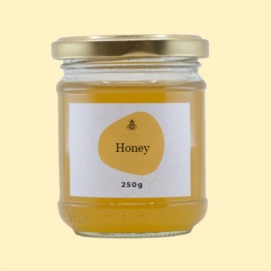 A small, transparent glass jar of honey with a gold lid. The label is white with a repeating honeycomb pattern. In the center of the label, there is an abstract, golden-yellow shape with a small illustration of a bee and the text "Honey". Below this, the text "250g" is printed. The jar is set against a plain, light yellow background.