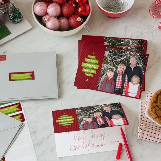 Christmas Card on table with hand written message, shipping labels, cookies and Christmas decoration