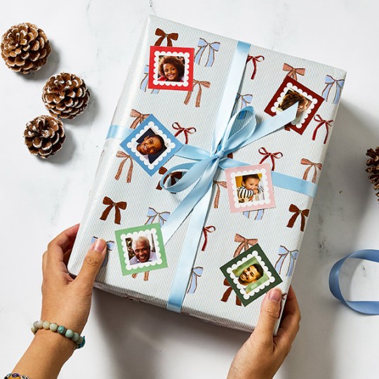 Personalised Christmas stickers of family faces on square stickers on a christmas present with a blue ribbon