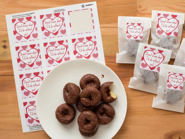 Love heart labels on small sweets bags, next to a plate with small donut looking cakes.