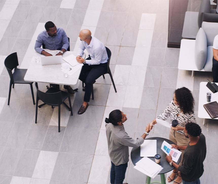 People sitting on tables conversing amongst each other at an event