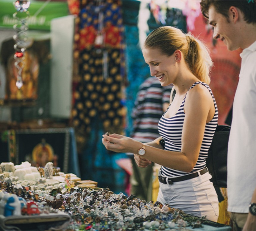 Woman and man standing before a table of handmade jewellery at a market