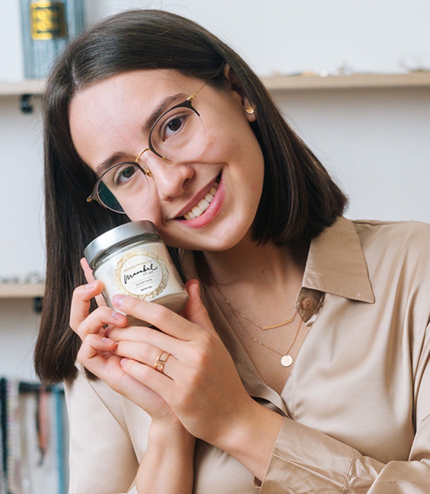 Woman smiling holding a candle jar with an Avery round label on it