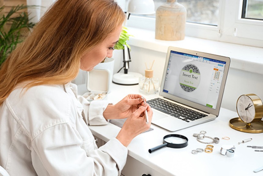 Woman at a desk making jewellery while her laptop displays Avery Design & Print software