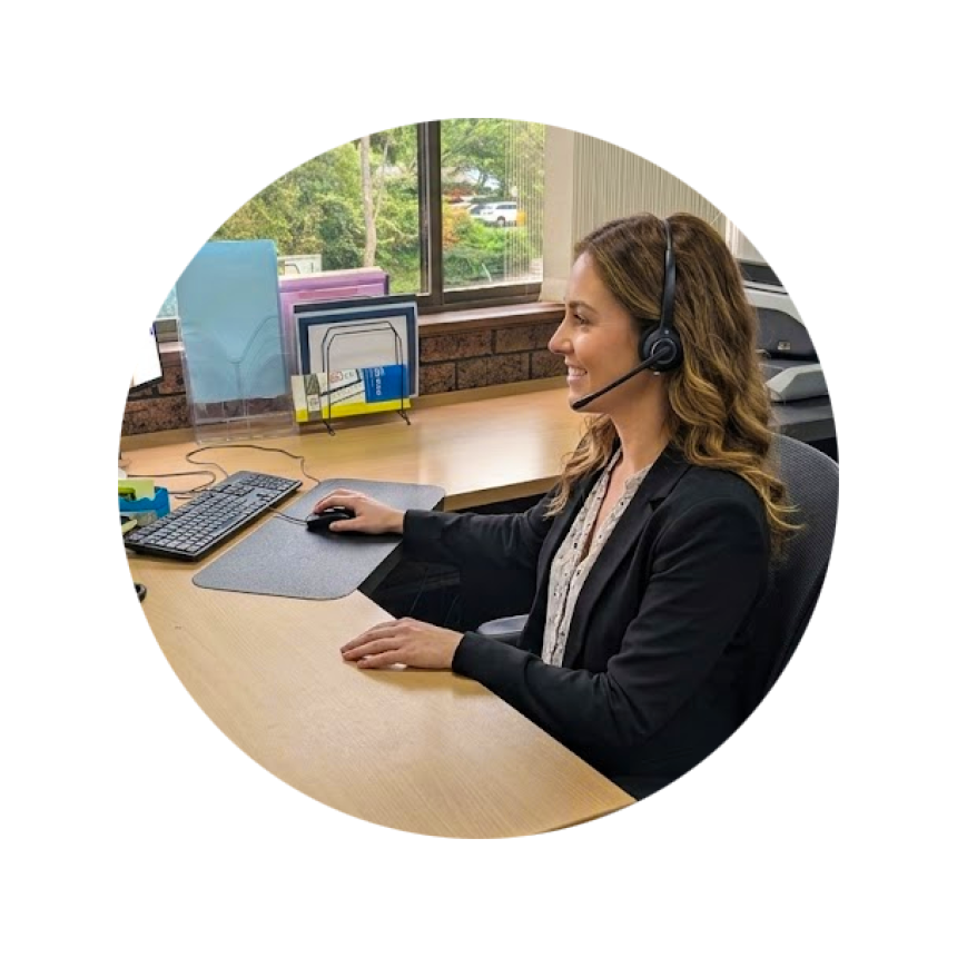 A young woman seated at her desk and speaking to a customer via her headset.
