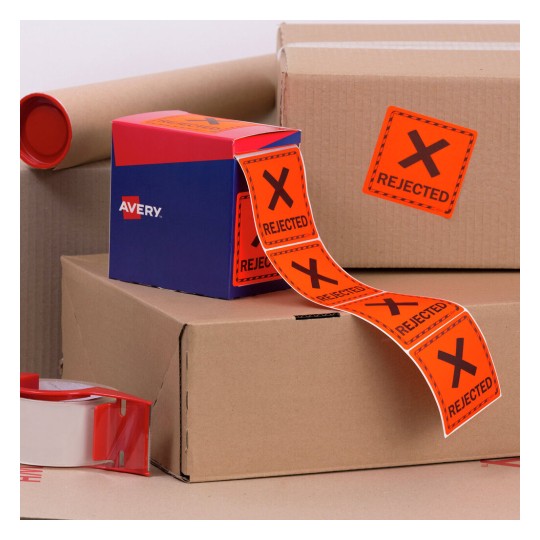 The image features cardboard boxes along with a box of labels. One label reads 'REJECTED' in bold on an orange background. There is packing tape visible, and the scene suggests packaging or shipping activities.