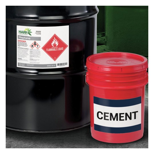 The image showcases a black drum labeled as containing heptane, which is a flammable liquid, alongside a red bucket marked 'CEMENT'. Both containers suggest use for construction or industrial purposes.