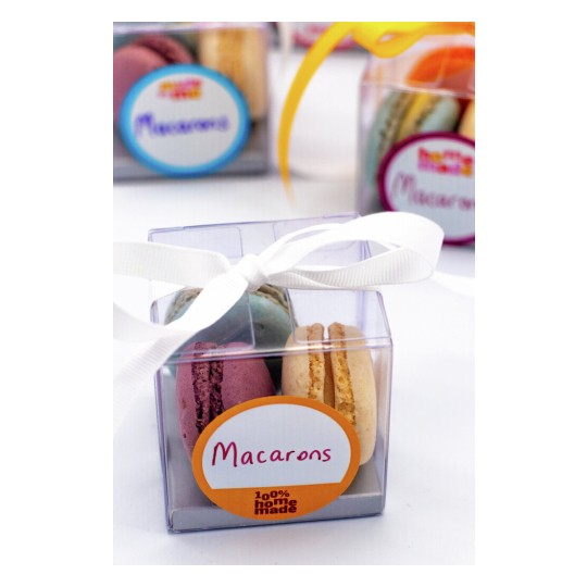 The image features a clear box containing colorful macarons with a ribbon on top. The box is labeled 'Macarons' and states '100% homemade'.