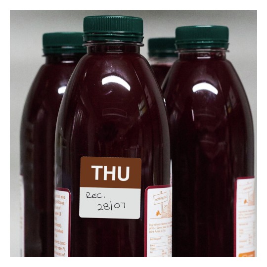The image features several bottles of reddish juice, each with a green cap. One of the bottles has a label indicating a day of the week (THU) and a date (28/07) along with some ingredient information on the side.