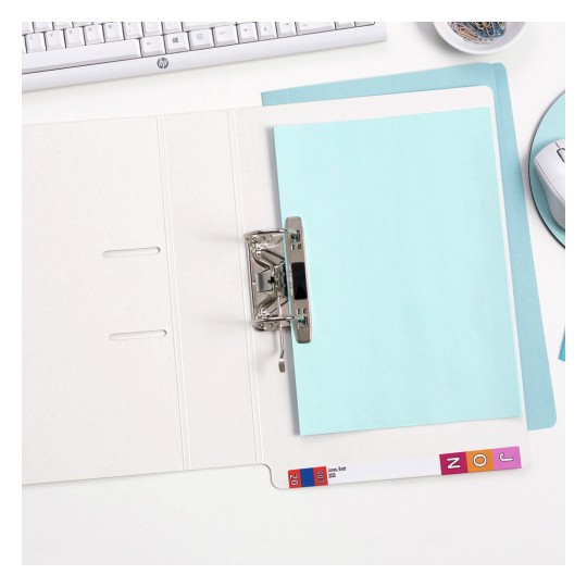 The image shows an open binder with a light blue sheet of paper inside, along with various office supplies such as a computer keyboard, a mouse, and a bowl of clips. The workspace is organized and minimalistic.