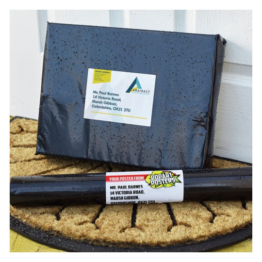 The image shows a package addressed to Mr. Paul Barnes with a label from 'Abstract Architecture' and a poster tube from 'PopArt Posters' on a welcome mat.