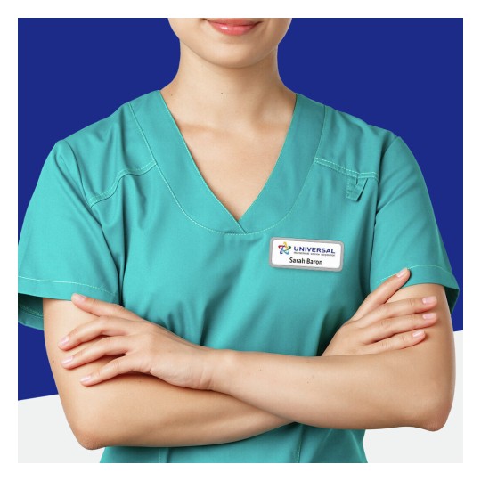 The image shows a person wearing a teal medical scrub top with crossed arms and a name tag. The background is a solid deep blue, making the individual stand out. The name tag indicates the name 'Sarah Baron' and the organization 'Universal Healthcare Corporation.'