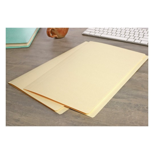 The image shows a wooden desk with two beige file folders lying on it. There is a keyboard and a coffee mug in the background, along with a turquoise notebook.