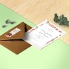 A6 card invitation to a wedding sitting on a desk with a brown envelope with a return address stuck on it. The card and the label have the same design.