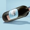 WePrint Arched Label applied to a wine bottle. Wine bottle floating on a graphically blue background.