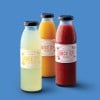 3 juice bottles on a blue background. Wrap around label around each bottle. The branding is Juice co.