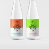 2 tall glass water bottle on a neutral background. Each bottle has a label on it.