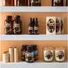 Retail shelving with different beauty and wellbeing products featured. Candles, jars, oil droppers, bottles. All with a brown and nature themed labels and branding.