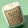 Green background with candle jar. On jar is a kraft brown label with the text Balsam Forest.