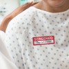 Covid Screening label applied to a hospital gown. The label is red with the words Screened and a spot for handwritten date and time.