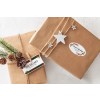 Sustainable Christmas presents wrapped in kraft paper with natural ribbon decorated in pine and ceramic star shapes labelled with christmas themed address stickers.