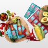 Mexican inspired labels on hot sauce bottle, corn, avocado and garnishes are scattered around.