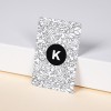 Business Cards leaning against a wall in a portrait position. Simple stylish design with the letter K in the middle of a black circle, and then graphically drawn leaves in background.
