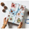 Personalised Christmas stickers of family faces on square stickers on a christmas present with a blue ribbon