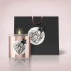 Round white label with black cursive writing, one stuck on a candle and the other on a gift bag.