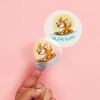 Transparent Sticker with a dog surfing and the word Moon Surf on a pink background with a finger you can see through stickers