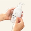 Hands applying a clear label on a pump plastic wash bottle