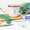 Clear removable label on a candle jar on table with foliage. Label sheets also on table