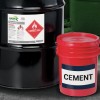 The image features a black barrel labeled as containing heptane, a flammable liquid, along with a red bucket clearly marked with the word 'CEMENT'. The items are placed on a surface with a slightly textured appearance.