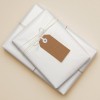 The image features two neatly wrapped presents in white paper, tied with twine. One of the gifts has a brown tag attached, suggesting a personalized touch. The background is a soft beige, adding to the overall aesthetics of the presentation.