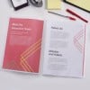 The image displays a document with sections titled 'Meet the Executive Team,' 'About Us,' and 'Mission and Vision.' The pages feature a pink background with geometric designs in yellow and teal. There are also office supplies like a pen, sticky notes, and a stapler in the background.