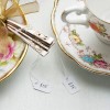 The image features a decorative plate with silver-colored utensils tied with a bow, and a delicate teacup beside it. Price tags indicate $55 and $35.