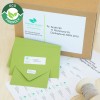The image features eco-friendly packaging, including a cardboard box and green envelopes. The box has shipping labels with addresses, and there are additional labels on display. The design emphasizes sustainability.