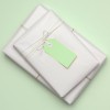 The image features two neatly wrapped packages in white paper, tied with twine. Each package has a green tag attached, resting on a light green background.